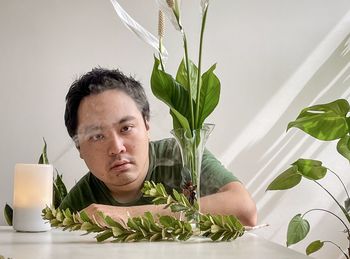 Portrait of young asian man with aromatherapy diffuser, peace lilies in vase and plants.