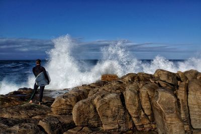 Rear view of man standing at sea shore against clear sky