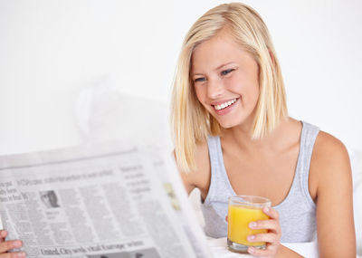 Portrait of smiling young woman using mobile phone against white background