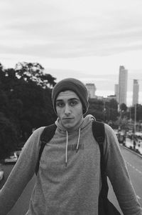 Portrait of young man standing against sky in city