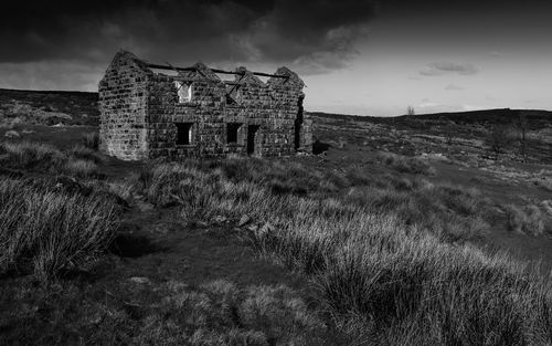 Old abandoned building on field against sky