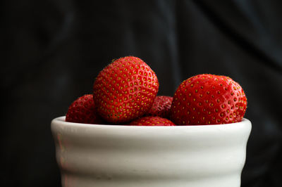 Close-up of strawberries in bowl against black background