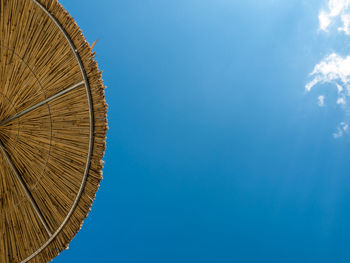 Low angle view of parasol against clear blue sky