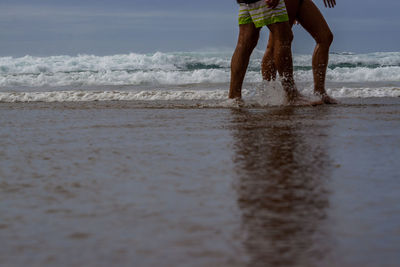 Low section of man standing on beach