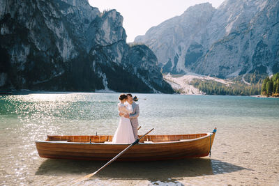 Man standing on boat in lake against mountains