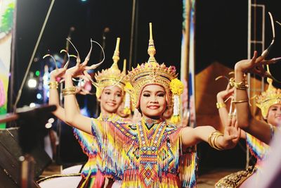 Smiling women in traditional clothing dancing on stage at night