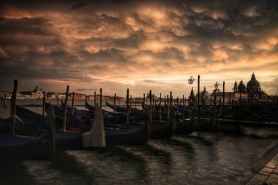 Boats moored in sea against cloudy sky during sunset