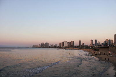 Scenic view of sea and buildings against clear sky