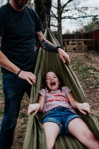 Dad pushing happy girl in hammock