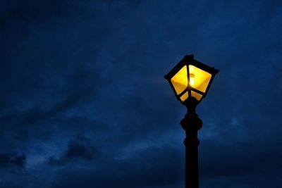 Low angle view of illuminated street light against sky