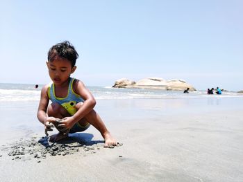 Full length of boy standing on beach against clear sky