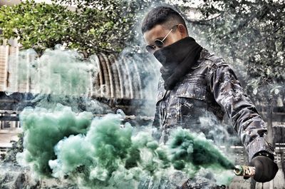 Young man holding distress flare while wearing scarf