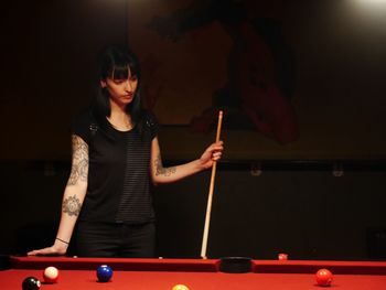 Young woman standing by pool table