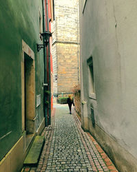 Rear view of woman walking on footpath amidst buildings