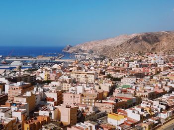 Aerial view of townscape by sea against clear blue sky