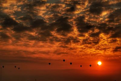 Low angle view of silhouette birds flying against dramatic sky