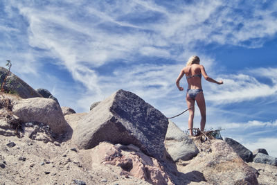 Woman standing on rock against sky