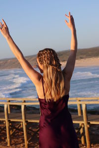 Rear view of woman at beach against sky