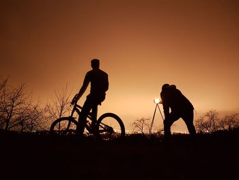 Silhouette man riding bicycle against sky during sunset
