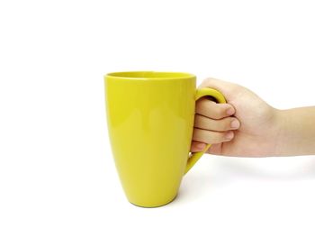 Close-up of hand holding yellow against white background