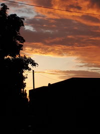 Low angle view of silhouette trees against orange sky