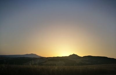 Scenic view of field against clear sky during sunset