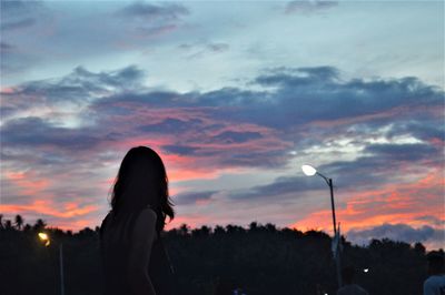 Silhouette woman standing against sky during sunset