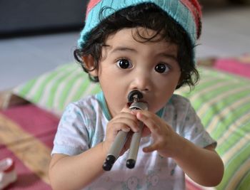 Close-up portrait of cute baby girl playing with tripod at home