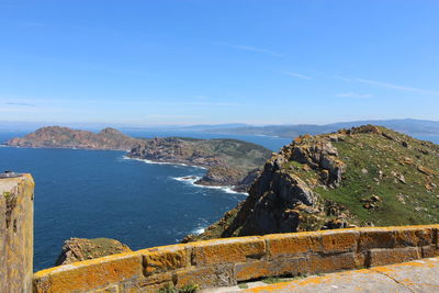 Scenic view of sea and mountains against blue sky