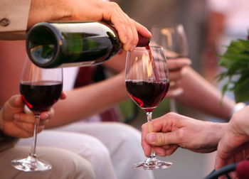 Cropped image of hand pouring red wine in glass