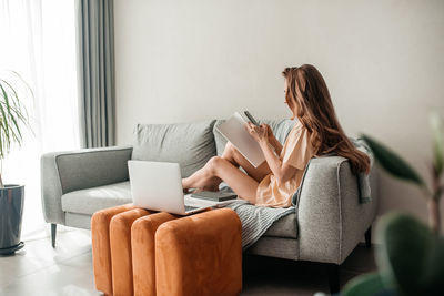 Woman using mobile phone while sitting on sofa at home