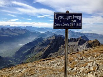 Information sign on mountain against sky