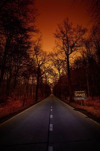 Road amidst trees against sky during sunset