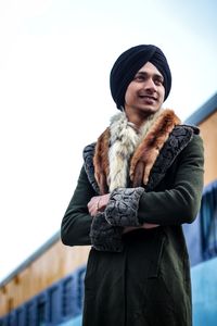 Young woman wearing hat standing against sky during winter