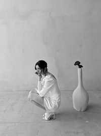 Side view of young woman standing against wall