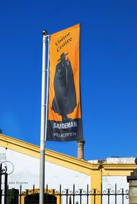 Low angle view of sign against blue sky