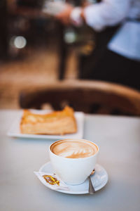 Cappuccino with snack served on table in cafe