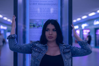 Fashionable young woman standing in illuminated built structure