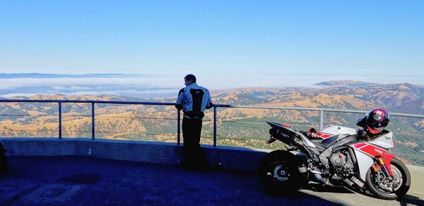 Rear view of man looking at mountains against sky