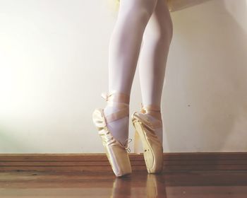Low section of ballet dancer standing on hardwood floor