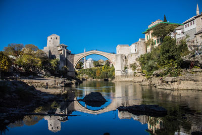 Arch bridge over water against blue sky