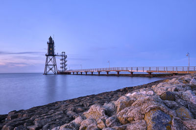 Lighthouse by sea against sky