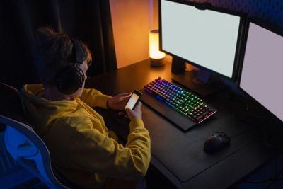 Boy using smart phone while playing video game on table at home