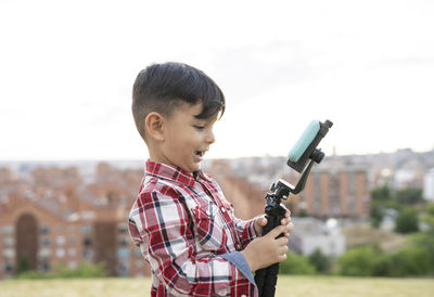 Side view of boy holding camera