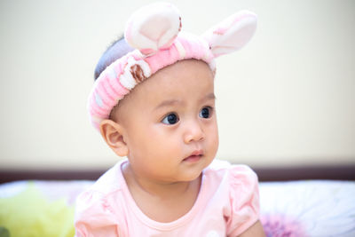 Cute baby girl wearing bunny ears headband at home