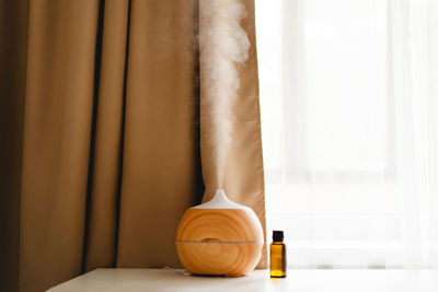 Aromatherapy concept. aroma oil diffuser on the table against the window.