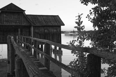 Wooden pier amidst trees and buildings against sky