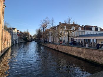 Canal amidst buildings in city against clear sky