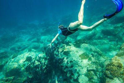 Woman snorkeling over rocks undersea