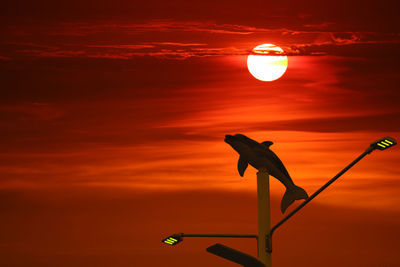 Close-up of silhouette light against orange sky